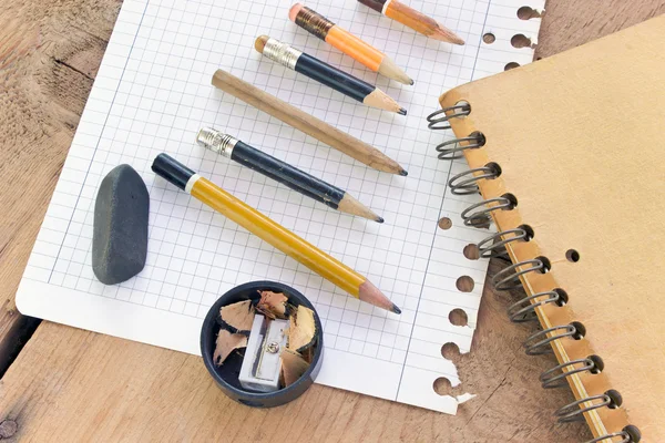 Used pencils and paper on wooden table — Stock Photo, Image