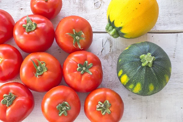 Tomatoes and zucchini on white wooden surface — Stock Photo, Image