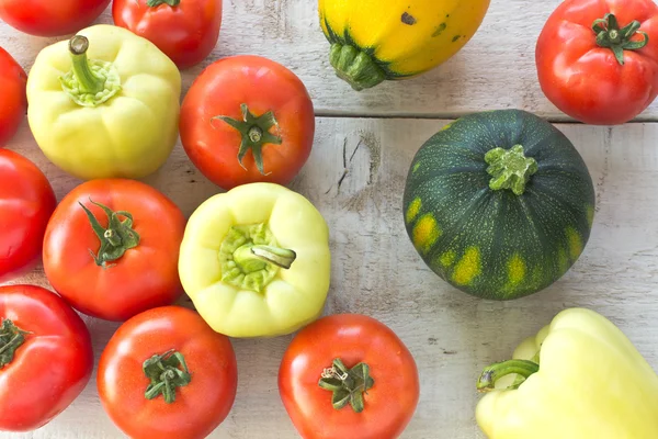 Tomatoes, pepper and zucchini on white wooden surface — Stock Photo, Image