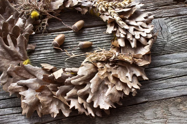 Grinalda de folhas de carvalho e bolotas em fundo de madeira — Fotografia de Stock
