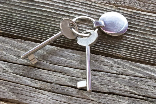 Ключі з металевою міткою на дерев'яному фоні — стокове фото