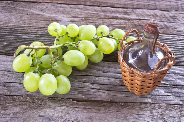 Old sealed bottle of wine and white grape on wooden background — Stock Photo, Image