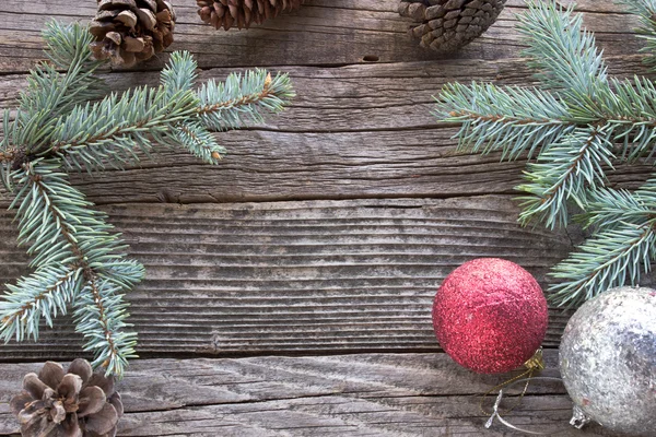 Pine cones, needles and Christmas balls on wooden background — Stock Photo, Image