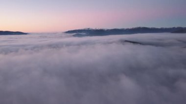 Gün batımında dağlarda manzaralı beyaz bulutların üzerinde uçmak