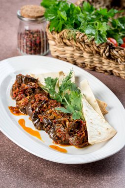 Patlıcan aperatifi, otlar ve beyaz tabakta yassı ekmek.