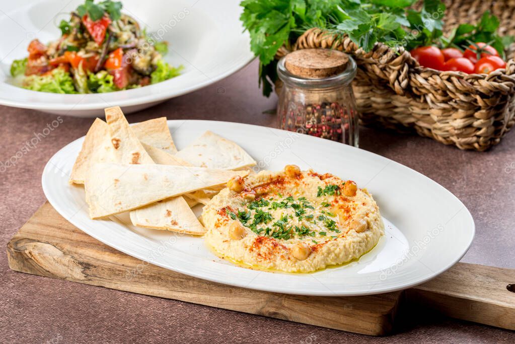Hummus with flatbread on white plate filmed for menu