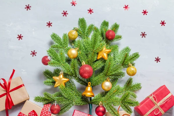 Zelený smrk větev zdobené vánoční hračky koule, hvězdy, jako vánoční strom s dárky na šedém betonu pozadí. Pohled shora. Veselé Vánoce a nový rok — Stock fotografie