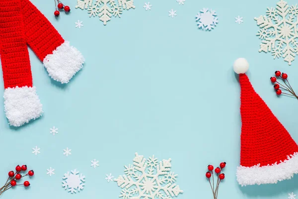 Cappello Babbo Natale rosso lavorato a maglia, sciarpa, fiocchi di neve e bacche rosse su sfondo blu, sotto forma di cornice. La vista dall'alto. Buon Natale, Capodanno — Foto Stock