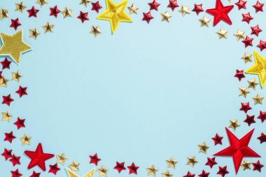 Altın, kırmızı ve sarı konfeti yıldızları mavi arka planda bir çerçeve şeklinde farklı boyutlarda. Noel, doğum günü ya da parti. Düz konum, üst görünüm, kopyalama alanı