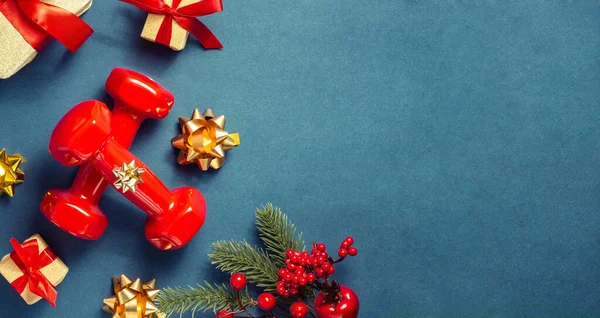 Fitness concept felice Natale e felice anno nuovo. Manubri rossi, inchini, regali con nastri rossi e un abete con bacche rosse su uno sfondo azzurro-verde, bokeh. Vista dall'alto, copia spazio — Foto Stock