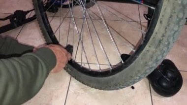 Adamın biri dağ bisikleti tekerleğini pompalıyor.