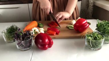 Bir kadın lezzetli, sağlıklı bir sebze salatası için biber keser.