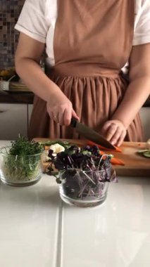 Bir kadın lezzetli, sağlıklı bir sebze salatası için havuç kesiyor. Dikey video.