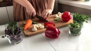 Bir kadın lezzetli, sağlıklı bir sebze salatası için biber keser.