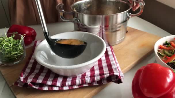 Wlewanie zupy z garnka do talerza za pomocą chochli — Wideo stockowe