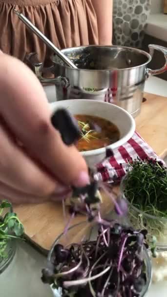 A woman sprinkles sprouts in a delicious beautiful soup — Stock Video
