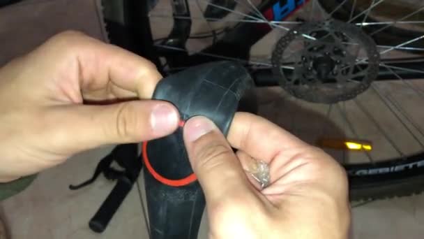 Мужчина проверяет, как он наклеил пластырь на колесо велосипеда — стоковое видео