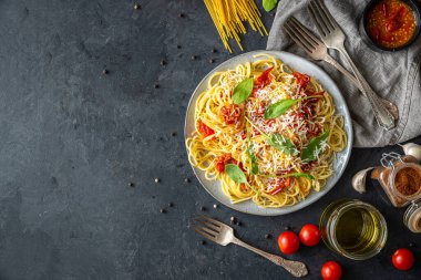 Seramik tabakta makarna ve siyah arka planda malzemelerle İtalyan yemeği. Düz görüş. Üst görünüm.