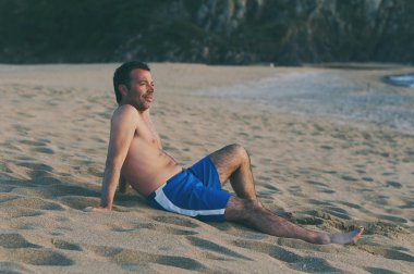 Gün batımı sahilde çalıştırdıktan sonra yakışıklı adam