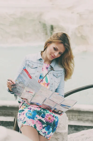 Pretty woman looking a touristic map near the fountain of Trevi — Stock Photo, Image