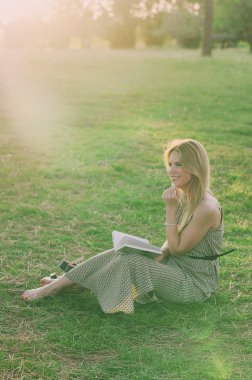 Bautiful genç kadın günbatımı parkta okuma