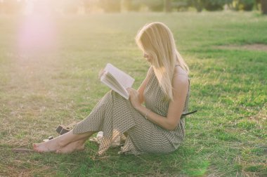Bautiful genç kadın günbatımı parkta okuma
