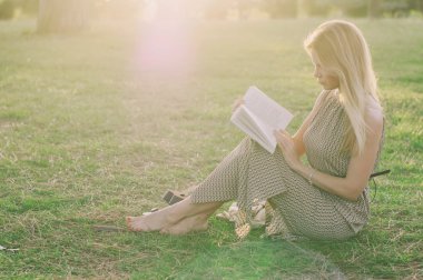 Bautiful genç kadın günbatımı parkta okuma