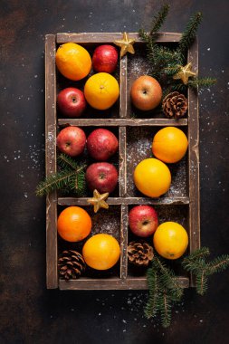 Noel konsepti. İçinde portakal, elma ve noel süslemesi olan ahşap kutu. Üst alt görünüm