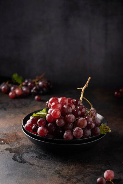 Концепция здоровой вегетарианской пищи. Красный виноград на черном столе, селективное фокусное изображение