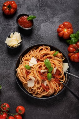 Siyah arka planda domates soslu, fesleğen ve peynirli geleneksel İtalyan makarnası.