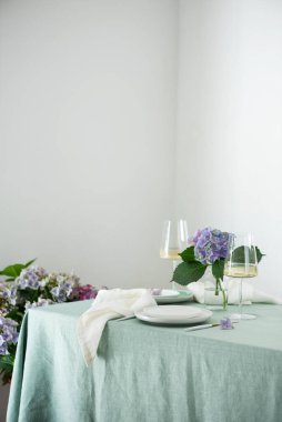 Yeşil keten masa örtüsü ve çiçeklerle el yapımı seramik tabaklar. Parti konsepti