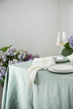 Yeşil keten masa örtüsü ve çiçeklerle el yapımı seramik tabaklar. Parti konsepti