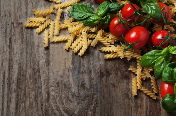 Alimentos italianos com fusilli cru, tomate, manjericão, queijo — Fotografia de Stock
