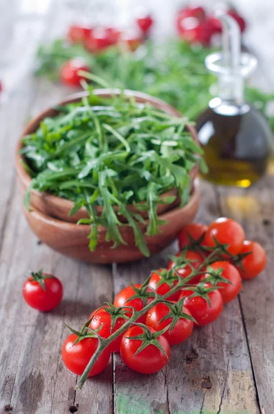 Arugula in bowl and tomatoes — Stock Photo, Image