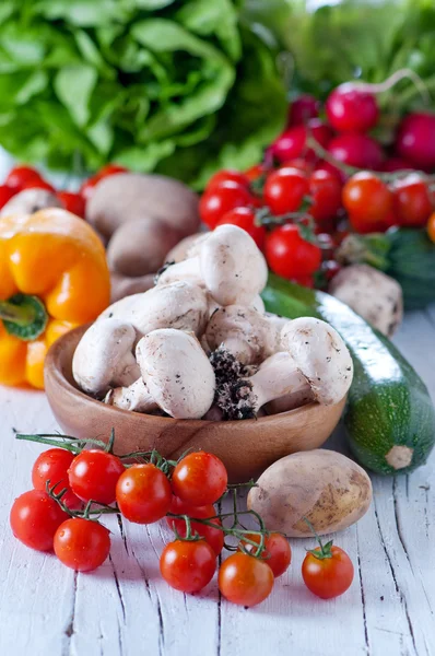 Mushrooms in a wooden bowl and vegetables — Stock Photo, Image