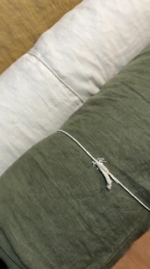 Ahşap bir masanın üzerinde çeşitli keten kumaşların dikey görüntüsü. Tekstil atölyesi, dikiş malzemeleri ve doğal kumaş seçimi konsepti.