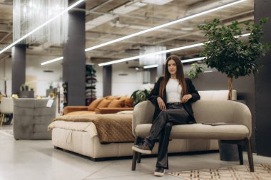 Profesyonel kıyafetli kendine güvenen bir kadın modern mobilya mağazasında şık ve rahat modern tasarımlar sergiliyor sofistike bir ambiyansı var..