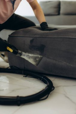 Profesyonel temizlikçi evdeki kirli kanepe yastığında ıslak süpürge kullanarak temizlik hizmeti veriyor.