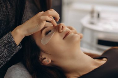 Bir kadın müşteri, bir güzellik uzmanından kirpik uzatma hizmeti alıyor. Güzellik ve profesyonel kozmetik prosedürüne odaklanma