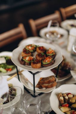 Kanepe aperatifleri ve çok katmanlı servis tabağında sunulan küçük lokmalar bir catering etkinliğinde misafirler için hazırdır.