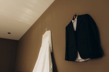 Gelinlik ve smokin bir düğün törenine hazırlanıyor. Evlilik, aşk ve ortaklığı simgeliyor.