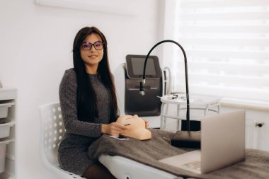 Manken kafası üzerinde kirpik eklentisi uygulayan genç kadın güzellik uzmanı, kuaförde yeni güzellik becerileri öğreniyor.