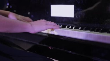 Siyah bir kuyruklu piyano çalan bir kadının elleri. Zarif ayar ve yetenekli çalma sofistike bir ortam yaratır..