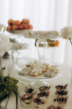 Bir etkinlik için çeşitli tatlılar, pastalar, meyveler ve bireysel tatlılar sunan zarif bir tatlı masası.