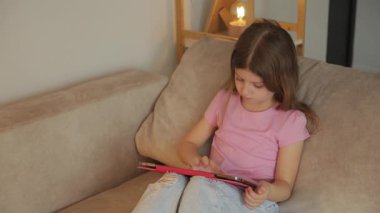 Genç bir kız, tabletine dalmış, rahat bir kanepeye oturur. Boş zamanlarını rahat bir ortamda, gezinerek ya da oyun oynayarak geçirir..