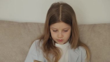 Genç bir kız kanepede oturup kitap okuyor. Sayfayı çevirip okumaya devam ediyor..