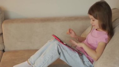 Genç kız evinde rahat rahat otururken tabletinde piyano çalıyor. Günlük kıyafetlerle..