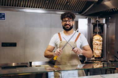 Şef önlük giyiyor ve bıçak tutuyor, çelik çubukla biliyor, fast food restoranında sokak yemeği hazırlıyor.