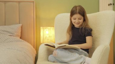 Genç bir kız rahat rahat bir koltukta oturur, büyüleyici bir kitapla büyülenir. Ilık lamba ışığı huzurlu bir atmosfer yaratır. Okuma akşamı için mükemmel bir ortam..
