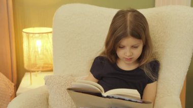 Genç bir kız rahat rahat bir koltukta oturur, lambanın altında büyüleyici bir kitaba dalmış..